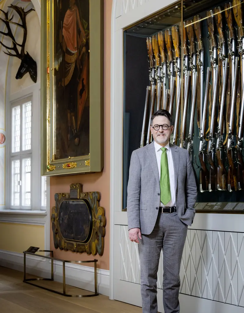 Mann vor einer Vitrine mit Gewehren