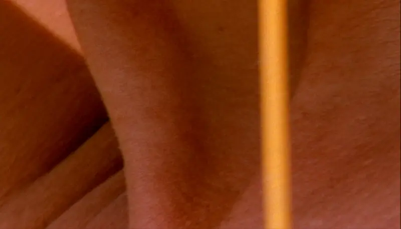 Es ist eine Videoausschnitt einer Nahansicht eines Halses zu sehen, erleuchtet in orangenem warmen Licht.