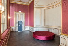 Blick in Raum mit roten Tapeten und rundem Sofa
