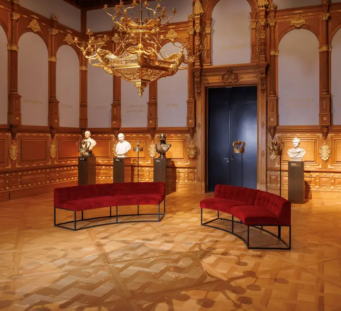 rotes Sofa, im Hintergrund Büsten von Männern