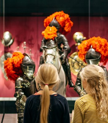 Zwei Kinder, die Ritterrüstungen von Kindern betrachten