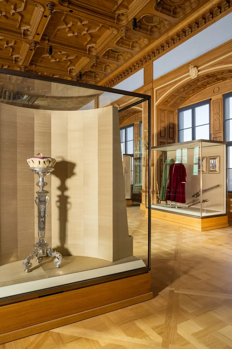 Raumansicht im Vordergrund Vitrine mit einer königlichen Kopfbedeckung