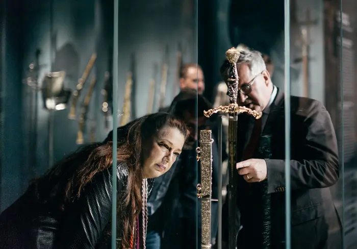 zwei Personen betrachten ein aufwendig verziertes Schwert mit Scheide