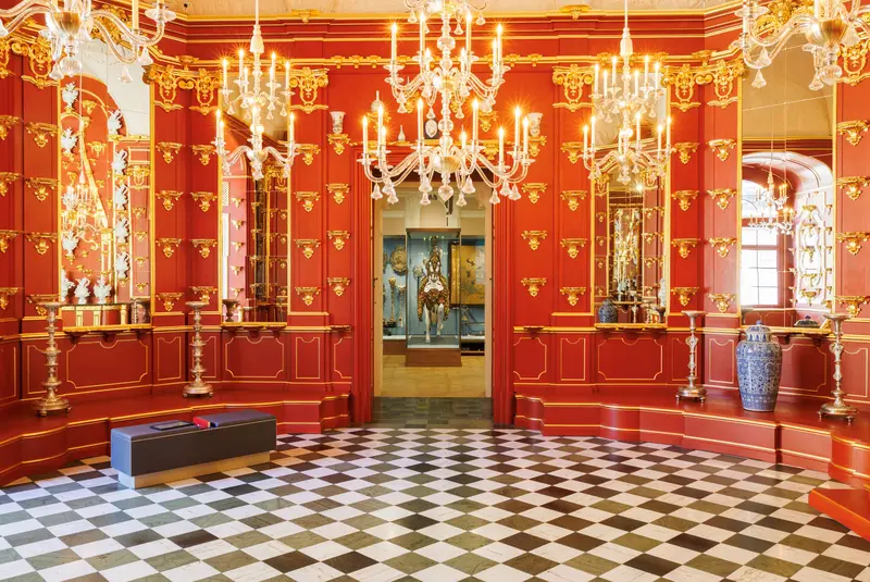 Raumansicht mit roten Wänden und goldenen Kronleuchtern